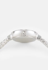Orologio in acciaio inox argento con cassa rotonda, lunetta testurizzata e bracciale a motivo a griglia. Design piatto dallo stile minimalista.