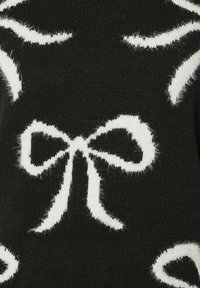 Czarna dzianina z białymi, puszystymi wzorami w postaci kokardek i wirów. Miękka tekstura w kontrastowym wzorze tworzy wizualne zainteresowanie.