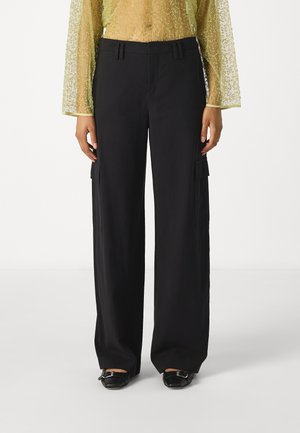 Schwarze, weit geschnittene Cargo-Hosen mit Seitentaschen, die eine glatte Textur und ein flaches Vorderdesign aufweisen. Getragen mit einem durchsichtigen, verzierten Oberteil.