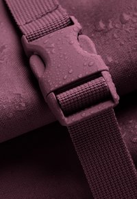 Cintura textured viola con una fibbia in plastica, caratterizzata da gocce d'acqua su una superficie liscia, che evidenzia la durata e la resistenza all'acqua.