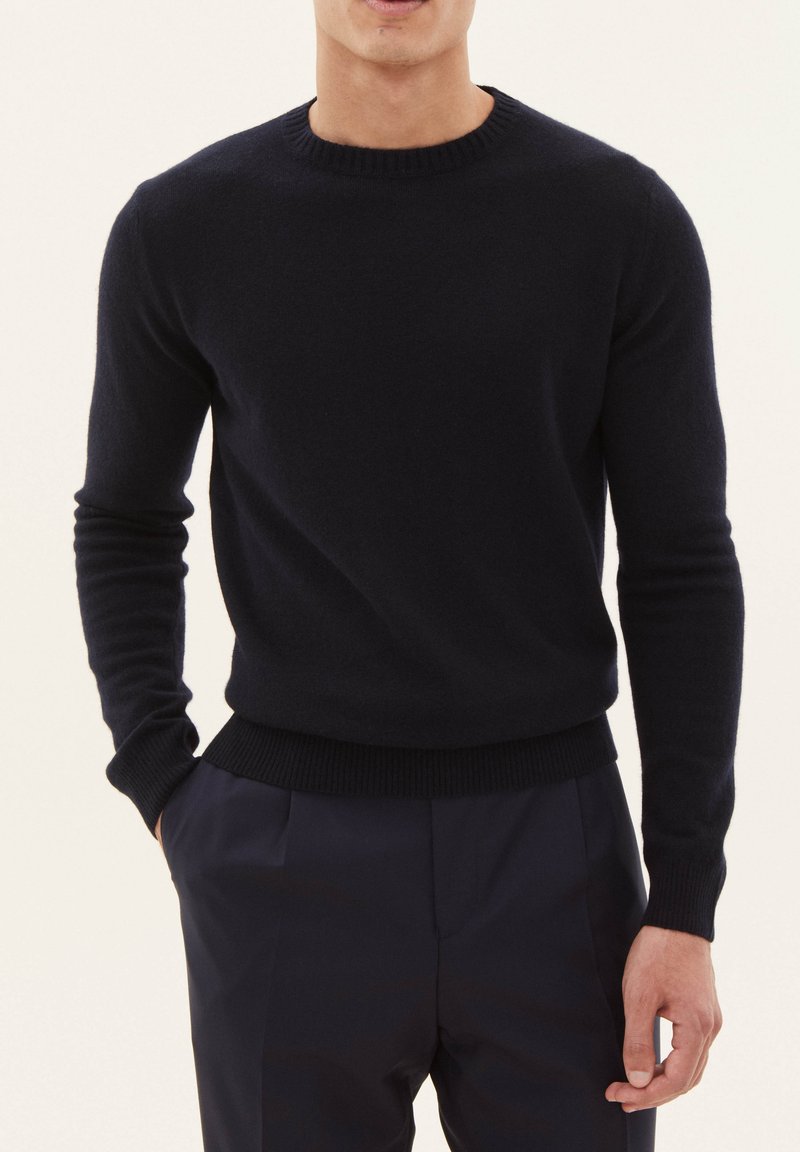 Navyblauer Wollpullover mit rundem Halsausschnitt, Rippbündchen und Saum. Slim-Fit-Design mit glatter Textur und minimaler Detailierung.