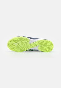 La suola della scarpa presenta un design testurizzato in giallo e grigio, con un motivo prominente per grip e stabilità. Costruzione leggera per prestazioni elevate.