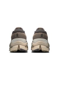 Hardloopschoenen met een bruine textiele bovenkant, lichtgrijze tussenzool en zwarte rubberen buitenzool. Heeft een gepolsterde kraag en logo-details.