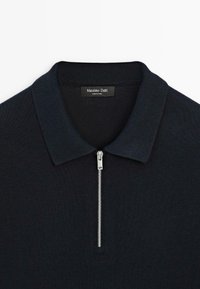 Czarny dzianinowy polo z pół zamkiem z przodu i ryżowym kołnierzykiem, oznaczony marką Massimo Dutti.