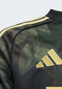 Crna i zelena kamuflažna majica s mrežastom teksturom, s zlatnim Adidas logotipom i tri pruge na ramenu.