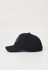 Mørkeblå bomullbaseballcap med buet skjerm, med brodert rød og gul detalj på frontpanelet. Seks ventilasjonsøyler.
