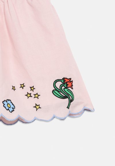 Ανοιχτό ροζ ύφασμα με κυματιστή βάση, κεντημένο με μπλε λουλούδια, κίτρινους αστερίσκους και πράσινα φύλλα με κόκκινα λουλούδια.