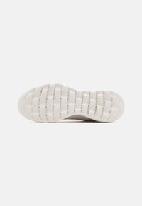Sole of a sneaker, featuring a flexible white rubber material with a textured pattern for grip and support. Smooth edge design.
