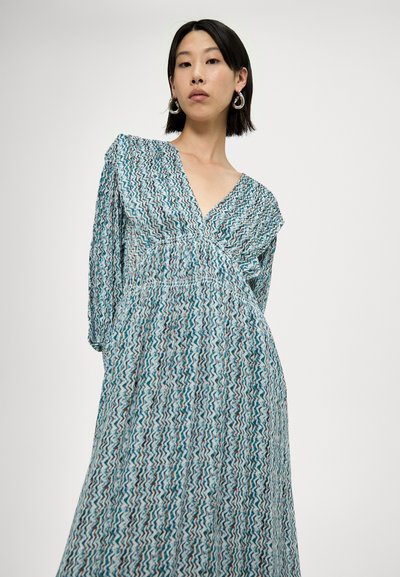 Rochie maxi cu decolteu în V, realizată dintr-un material ușor, cu un model în zigzag turcoaz și alb. Mâneci lungi și un design cu talie strânsă.