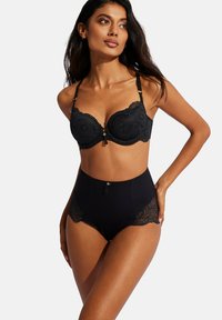 Zwarte kant beha met gevoerde cups en verstelbare bandjes; gecombineerd met hooggesneden panties met kantdetails en een gestructureerde zwarte stof.