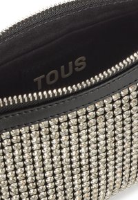 Czarna saszetka na zamek błyskawiczny z teksturowaną powierzchnią ozdobioną srebrnymi cyrkoniami, z gładką podszewką wewnętrzną z etykietą "TOUS".