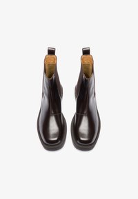 Rudi odiniai chelsea batai su lygia apdaila, elastingais šoniniais intarpais ir kilpos. Padas yra tekstūruotas, kad užtikrintų sukibimą.