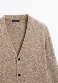 Cardigan lavorato a maglia di colore marrone chiaro con scollatura a V, caratterizzato da un motivo testurizzato e tre bottoni neri sul davanti. Materiale in morbido misto lana.