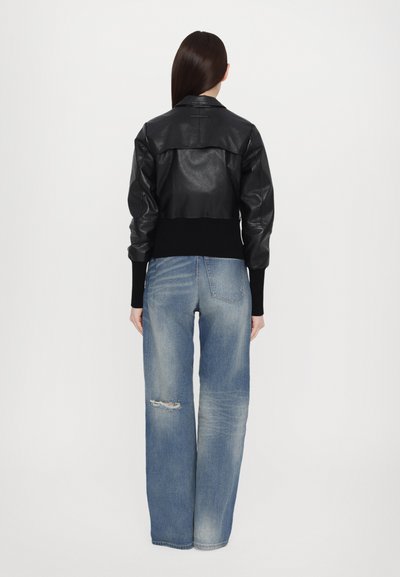 Black leather cropped jacket with ribbed cuffs and hem, paired with light blue distressed wide-leg jeans. Clean, modern design.