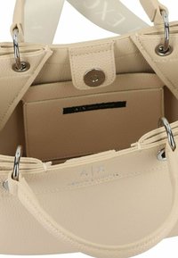 Borsa a mano in pelle beige con finitura testurizzata, hardware in argento e apertura superiore. Presenta una tasca interna e un'impronta del logo.