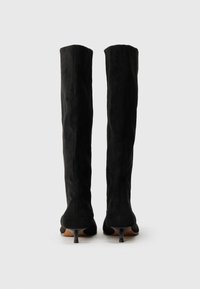 Knee-high black suede boots with a fitted design, pointed toes, and thin stiletto heels. Smooth texture with minimal accents.