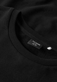 Sudadera negra de cuello redondo con cuello acanalado y etiqueta de tamaño visible marcada "11-12A 146-152" en el interior del escote.