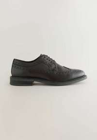 Chaussure de ville en cuir noir avec une finition texturée, design à bout ailé et détails perforés. Semelle en caoutchouc plate avec un léger talon.