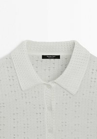 Biały dzianinowy krótki rękaw z kołnierzykiem w szpic, zapięciem na guziki i ażurowym, fakturowanym wzorem, oznaczony marką Massimo Dutti.