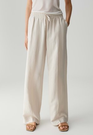 Cream, wide-leg trousers with an elastic waistband and drawstring. Smooth texture with two side pockets and a relaxed fit.