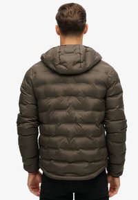 Pufferjakke i mørk oliven green, med kviltet design, fasthæftet hætte og elastiske manchetter. Glat, vandafvisende stof.