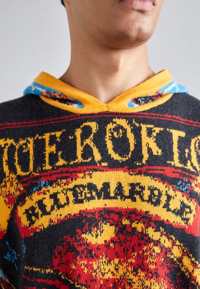 Colorful knitted hoodie featuring a black base, bright yellow accents, and intricate red and blue patterns; has a drawstring hood.