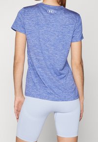 Blå heathered sportt-shirt med kort ärm, rundad halsringning och logotypdetalj på baksidan, ihop med ljusblå åtsittande shorts.