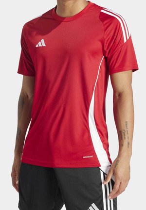 Homme portant un t-shirt de sport rouge à manches courtes avec des panneaux latéraux blancs et un short noir avec des bandes blanches.