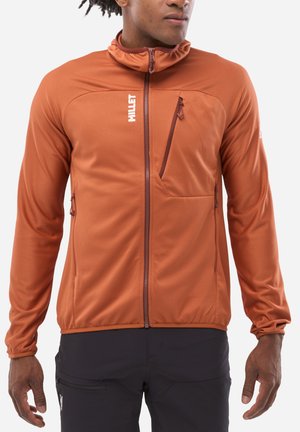 Orange zip-up jacket with high collar, fitted design, textured fabric, and zippered pockets. Features a logo on the chest and subtle stitching.