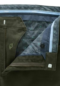Pantalons vert olive en velours côtelé texturé, dotés d'une doublure en motif matelassé bleu et gris, fermeture éclair et un logo en forme de feuille.