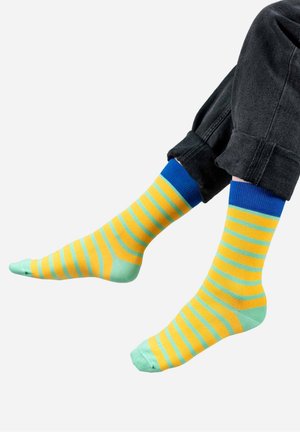 Świecące skarpetki w żółte i zielone paski, z niebieskim ściągaczem. Wykonane z miękkiego materiału, z równymi paskami i gładką fakturą.