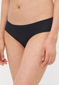 Zwarte bikini slipjes met een gemêleerd patroon, lage snit en naadloze randen voor comfort, gemaakt van een zachte, rekbare stof.
