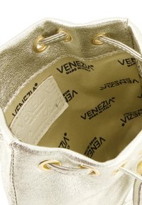 Metaliczne złote botki za kostkę o teksturowanym wykończeniu, z złotymi oczkami, sznurowanym zapięciem oraz wnętrzem wyściełanym materiałem z logo.
