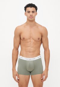 Boxer briefs i olivengrøn, lavet af blødt materiale. Elastisk livrem med "TOMMY HILFIGER" logo trykt i sort og røde detaljer.