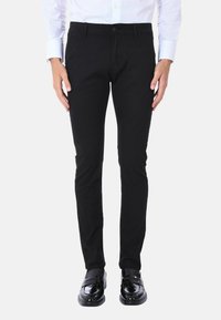 Pantaloni neri slim-fit realizzati in un tessuto testurizzato, dotati di un classico bottone di chiusura, tasche anteriori e una silhouette sartoriale.