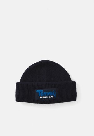 Knit beanie in dark navy with a ribbed texture. Features a rectangular patch with "Tommy Jeans, N.Y." in blue and white lettering.