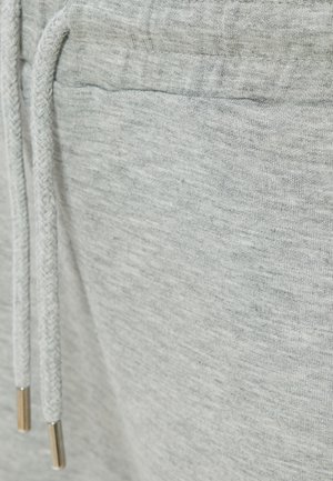 Jasnoszare dresy z miękkiego materiału, z sznurkiem ściągającym z metalowymi końcówkami i gładką teksturą. Brak widocznych logo lub wzorów.