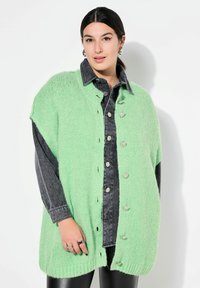 Mintgrön överdimensionerad stickad cardigan med knappar, i kombination med en mörk denimskjorta. Slät textur och lös passform, med sidoflikar.