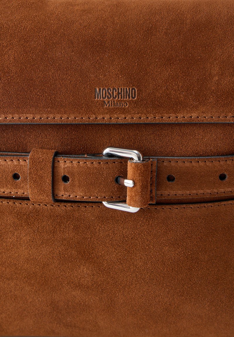 Sac en cuir suédé brun avec une bandoulière ceinturée cousue et une boucle en argent, embossé du logo "MOSCHINO Milano".