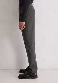 Grijze wollen broek met een rechte snit, voorzien van zijzakken, een paspel achterzak en een gladde textuur. Gecombineerd met zwarte veterschoenen.