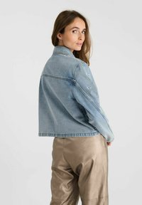 Lichtblauwe spijkerjack met een cropped design en zichtbare stiksels. Voorzien van subtiele logo borduursels op de mouwen en een klassieke kraag.