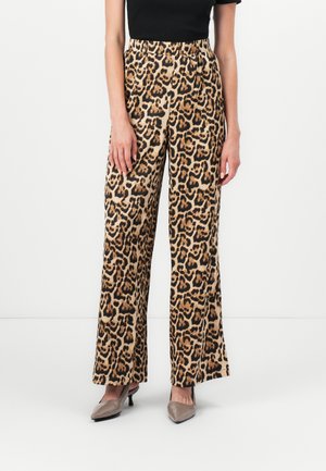 Pantalons à jambes larges en imprimé léopard dans un tissu beige et noir. Dotés d'une taille haute et d'une texture lisse. Associés à des chaussures grises à bout pointu.