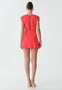 Mini abito rosso corallo con maniche corte, vita aderente e dettaglio con cerniera sul retro. Tessuto liscio con silhouette a gonna svasata.