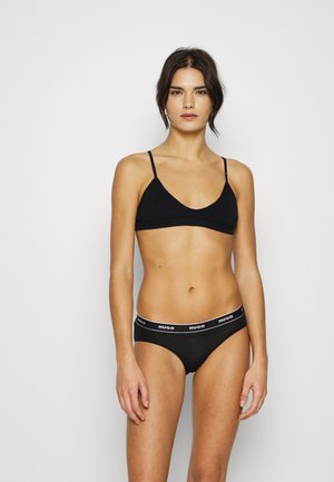 Ensemble de lingerie noire comprenant un bralette avec des fines bretelles et une culotte assortie avec une bande de logo blanche. Tissu doux et lisse, design simple.