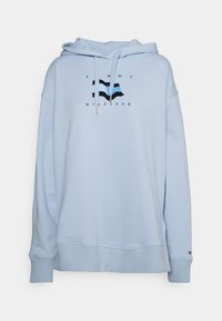 Sudadera azul claro hecha de una mezcla de algodón, que presenta un gráfico frontal de un diseño de bandera y el texto "TOMMY HILFIGER". Incluye capucha con cordón.