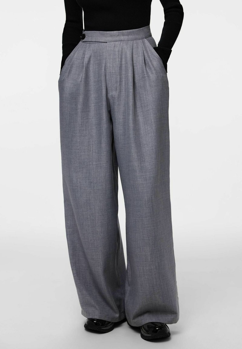 Szare spodnie o szerokich nogawkach wykonane z fakturowanej tkaniny, z plisami, kieszeniami po bokach oraz pojedynczym zapięciem na guzik w pasie.