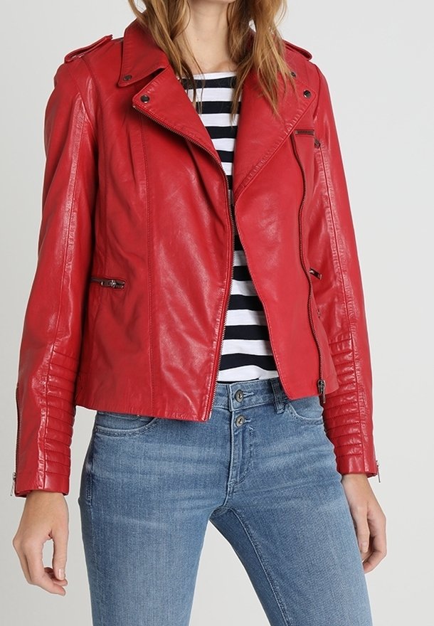 Giacca da biker in pelle rossa con un design aderente, zip asimmetrica e dettagli a coste sulle maniche, abbinata a una maglietta a righe e jeans blu.