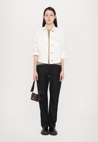 Bela denimska jakna s srebrnimi gumbi, olivno zelena majica, temno modri hlače, burgundska lakasta torbica in črne platforme.