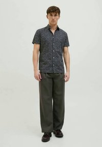 Kurzärmliges, marineblaues Hemd mit floralem Muster, kombiniert mit lockeren grauen Hosen. Das Outfit wird durch dunkle Schuhe ergänzt.