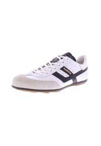 Witte sneaker met suède neuskap, zwarte accenten en veters. Heeft een gewatteerde kraag en een gouden logo. Rubberen zool met een gestructureerde grip.